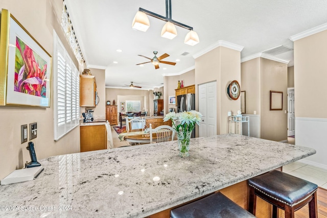 kitchen with pendant lighting, a kitchen breakfast bar, kitchen peninsula, and crown molding