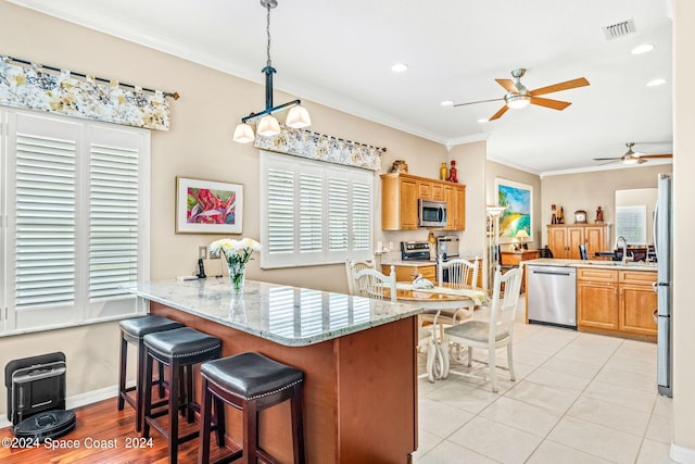 kitchen with kitchen peninsula, appliances with stainless steel finishes, crown molding, pendant lighting, and light tile patterned flooring