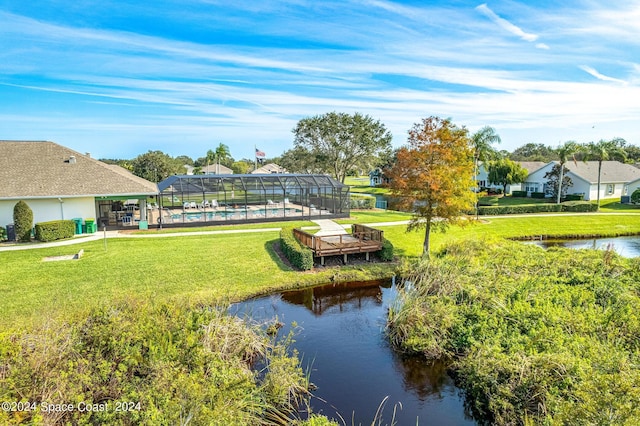 view of property's community with a lawn, a pool, and a water view