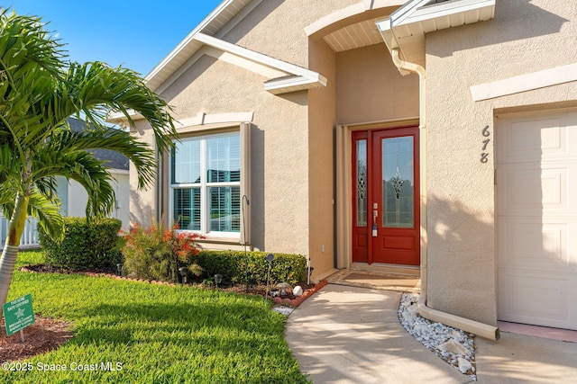 view of exterior entry with an attached garage and stucco siding