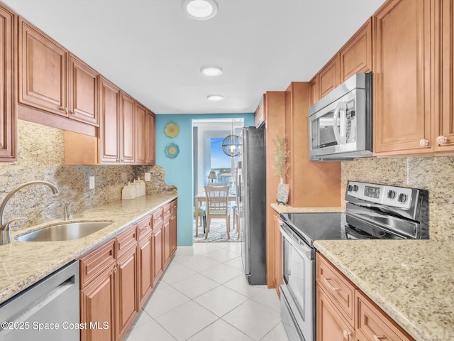 kitchen featuring tasteful backsplash, light stone counters, stainless steel appliances, sink, and light tile patterned flooring