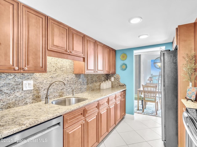 kitchen with light stone countertops, sink, stainless steel appliances, tasteful backsplash, and light tile patterned floors