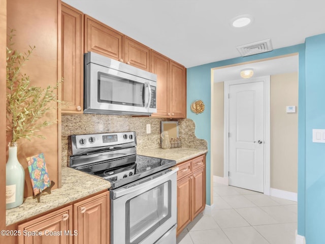 kitchen featuring tasteful backsplash, light stone counters, light tile patterned flooring, and appliances with stainless steel finishes