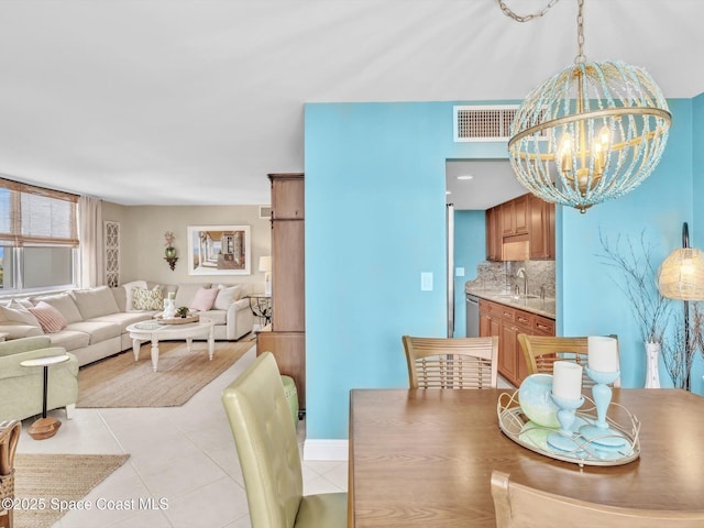 dining area with a notable chandelier, light tile patterned floors, and sink