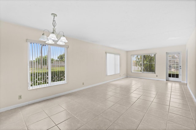 tiled empty room with plenty of natural light and an inviting chandelier