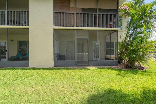 rear view of property featuring a lawn and a sunroom