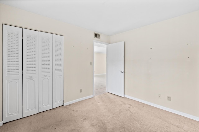 unfurnished bedroom featuring light colored carpet and a closet