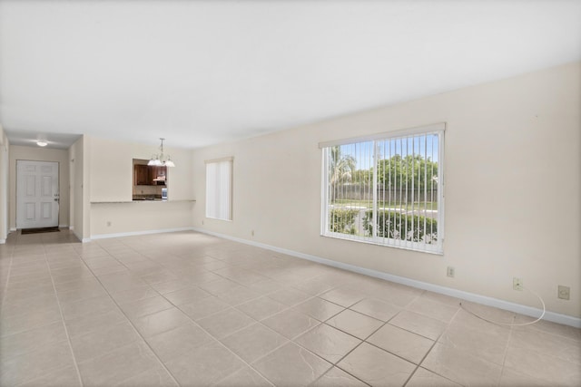 tiled empty room with an inviting chandelier