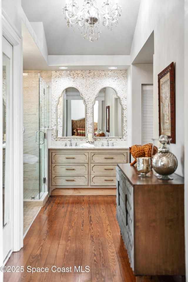 bathroom with hardwood / wood-style flooring, walk in shower, vanity, and an inviting chandelier