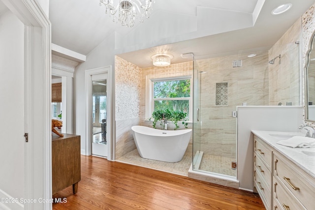 bathroom with lofted ceiling, vanity, an inviting chandelier, hardwood / wood-style flooring, and shower with separate bathtub