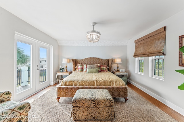 bedroom featuring access to exterior, wood-type flooring, french doors, and multiple windows