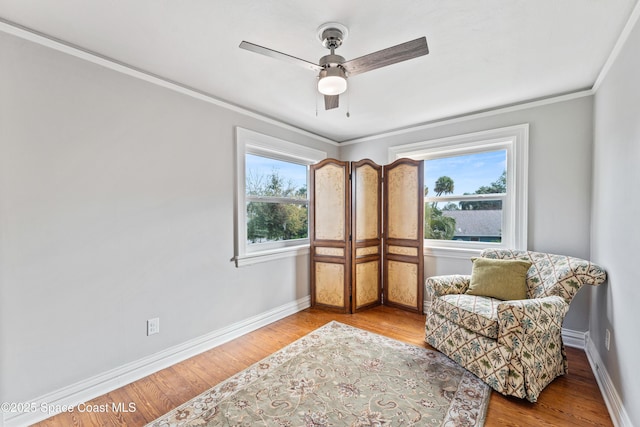 sitting room featuring light wood-type flooring, ceiling fan, a wealth of natural light, and ornamental molding