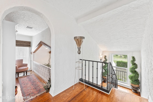 staircase with a textured ceiling and hardwood / wood-style floors