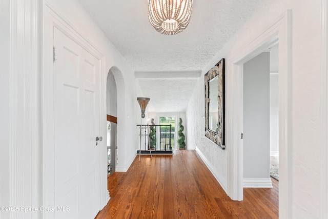 corridor featuring wood-type flooring, a textured ceiling, and a chandelier