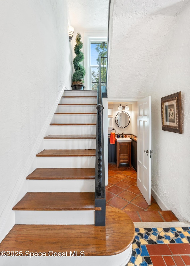 stairway with a textured ceiling and sink