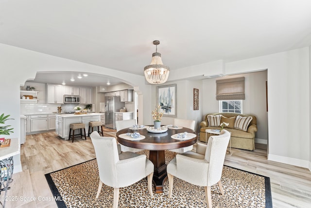 dining space with a notable chandelier and light hardwood / wood-style flooring