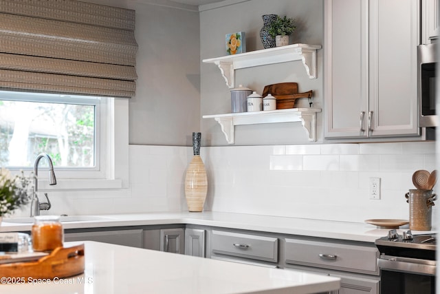 kitchen with decorative backsplash, sink, gray cabinetry, and stainless steel appliances