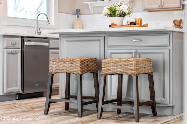 bar featuring decorative backsplash, sink, gray cabinets, and light hardwood / wood-style flooring