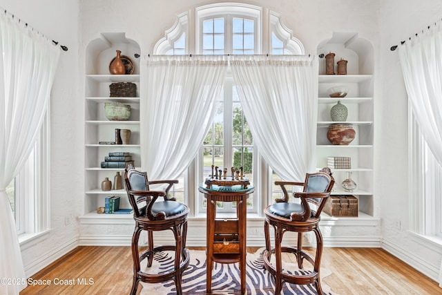 sitting room with hardwood / wood-style flooring and built in shelves