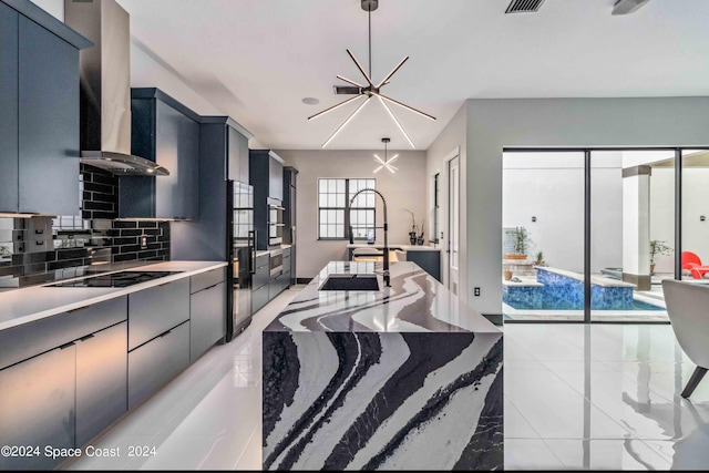 kitchen featuring an inviting chandelier, tasteful backsplash, dark stone counters, black electric stovetop, and exhaust hood