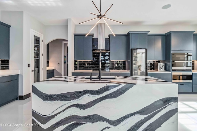 kitchen featuring tasteful backsplash, stainless steel fridge, wall chimney exhaust hood, and double oven