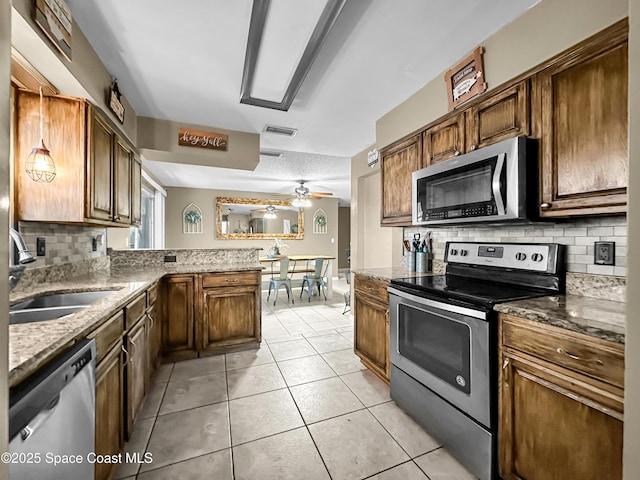 kitchen featuring ceiling fan, pendant lighting, decorative backsplash, sink, and appliances with stainless steel finishes