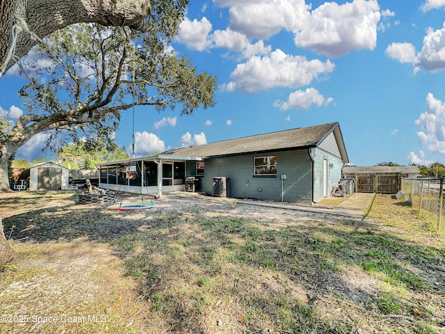 rear view of house with a patio area, a sunroom, a storage unit, and central AC