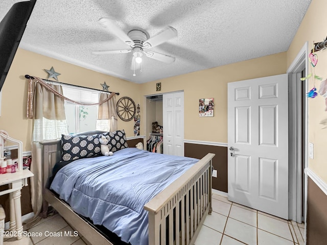 bedroom featuring ceiling fan, a closet, light tile patterned flooring, and a textured ceiling