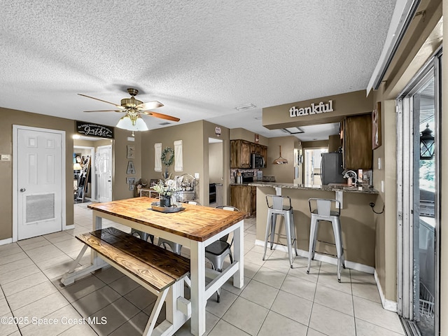 dining area with a textured ceiling, ceiling fan, and light tile patterned floors