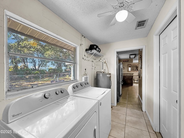 clothes washing area featuring ceiling fan, electric water heater, separate washer and dryer, a textured ceiling, and light tile patterned floors