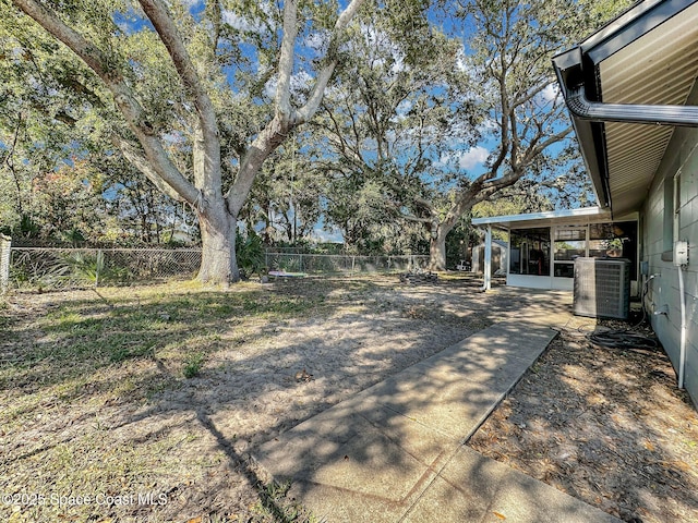 view of yard featuring a sunroom, cooling unit, and a patio