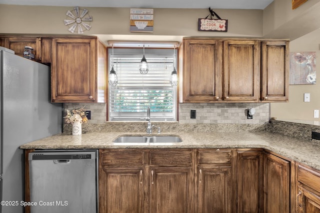 kitchen with stainless steel appliances, backsplash, decorative light fixtures, light stone counters, and sink