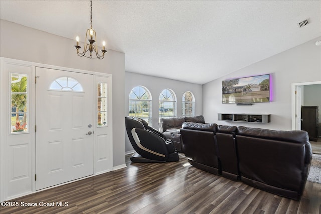 foyer with vaulted ceiling, dark wood-type flooring, a chandelier, and a textured ceiling