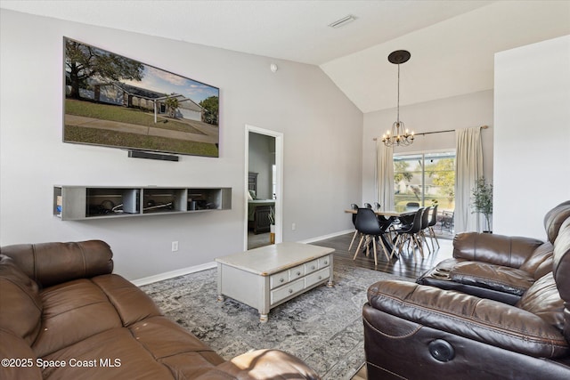 living room with an inviting chandelier, lofted ceiling, and hardwood / wood-style flooring