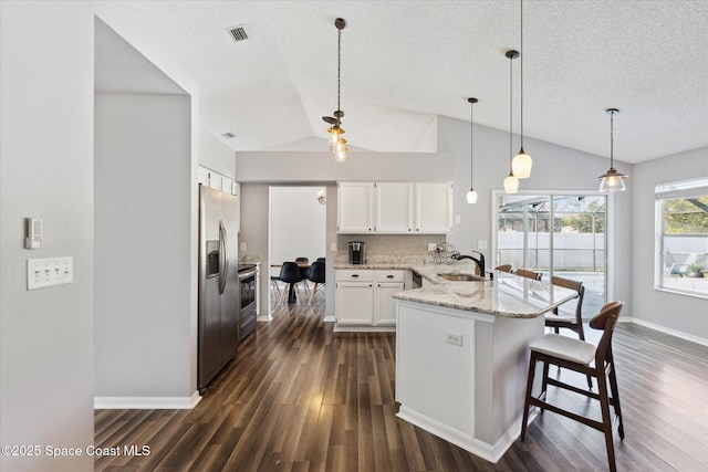 kitchen featuring pendant lighting, sink, white cabinetry, stainless steel appliances, and light stone countertops