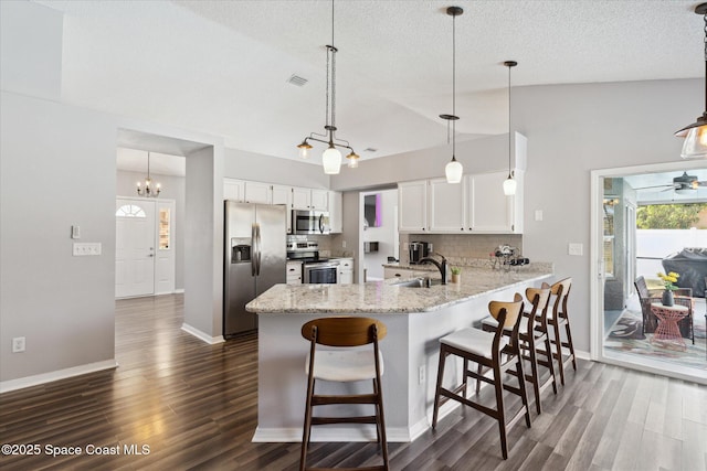 kitchen with sink, decorative light fixtures, appliances with stainless steel finishes, kitchen peninsula, and white cabinets