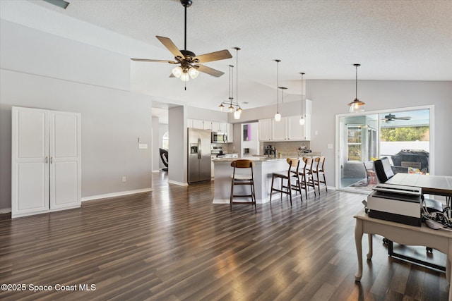 living room with ceiling fan, high vaulted ceiling, a textured ceiling, and dark hardwood / wood-style flooring