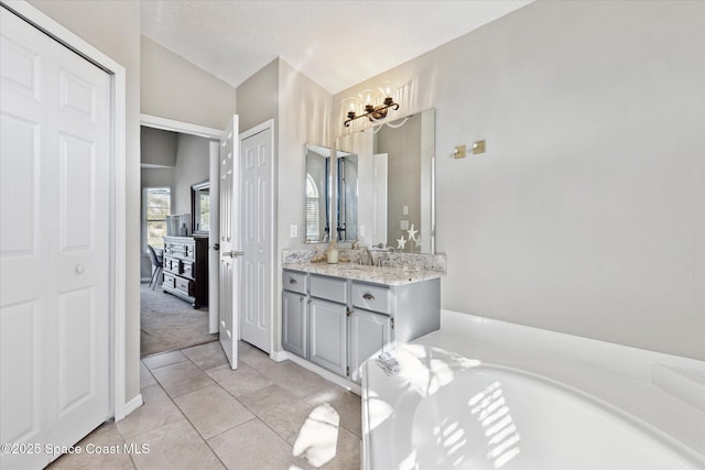 bathroom featuring vaulted ceiling, a textured ceiling, vanity, a bathing tub, and tile patterned flooring