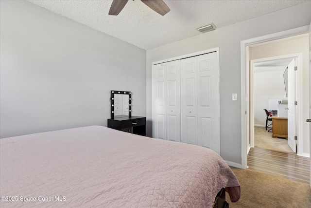 carpeted bedroom with ceiling fan, a textured ceiling, and a closet