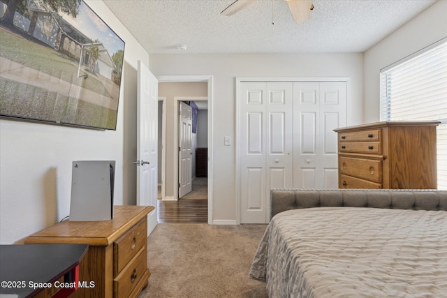 carpeted bedroom featuring ceiling fan, a closet, and a textured ceiling