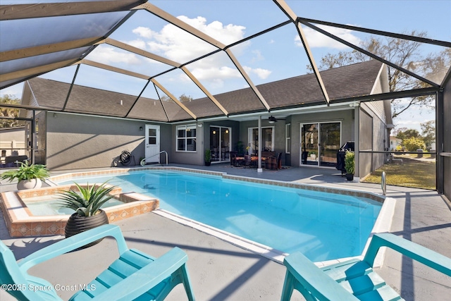 view of swimming pool with an in ground hot tub, ceiling fan, a patio, and glass enclosure