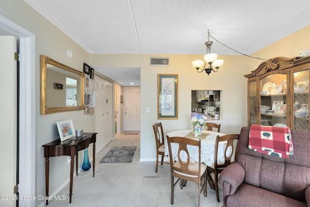 dining space with a textured ceiling, light tile patterned floors, and an inviting chandelier