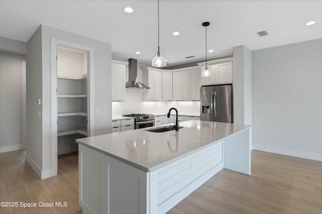 kitchen with sink, white cabinets, decorative light fixtures, stainless steel appliances, and wall chimney exhaust hood