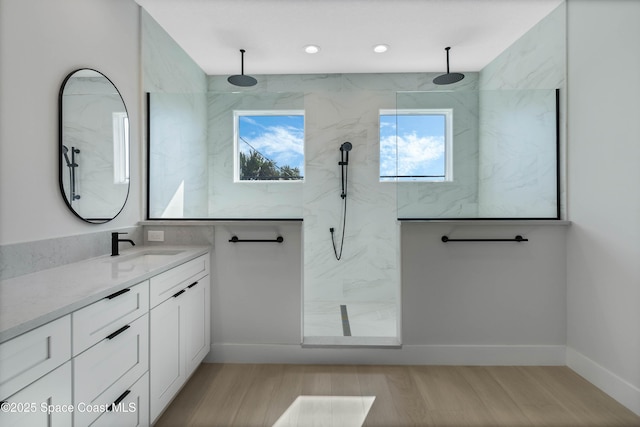 bathroom featuring vanity, a tile shower, and wood-type flooring