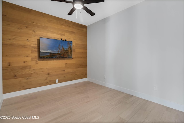 spare room with ceiling fan, hardwood / wood-style floors, and wood walls