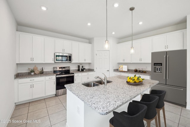 kitchen featuring white cabinetry, sink, stainless steel appliances, an island with sink, and pendant lighting