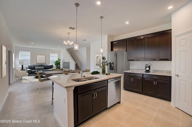 kitchen featuring sink, pendant lighting, a kitchen island with sink, dark brown cabinets, and appliances with stainless steel finishes