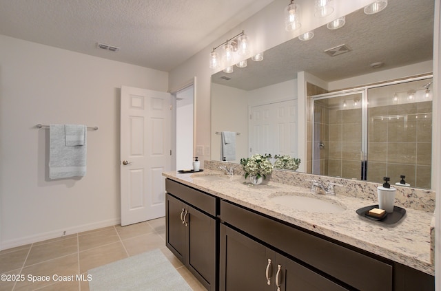 bathroom featuring tile patterned floors, vanity, a shower with shower door, and a textured ceiling