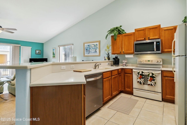 kitchen with kitchen peninsula, lofted ceiling, appliances with stainless steel finishes, light tile patterned flooring, and sink