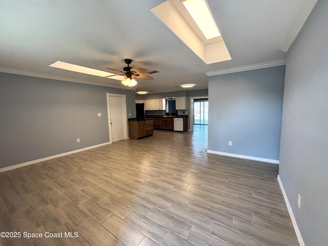 unfurnished living room with ceiling fan, a skylight, and crown molding